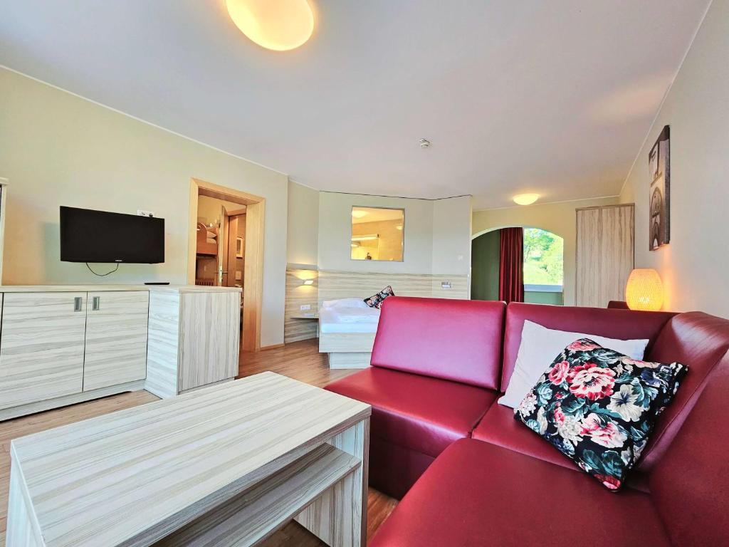 a living room with a red couch and a bed at Familienhotel Trebesingerhof in Trebesing