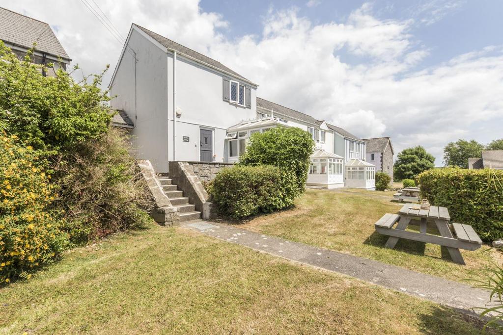 a house with a picnic table in the yard at Saddlers Cottage with indoor pool, tennis court and lots more Tenby area in Saint Florence