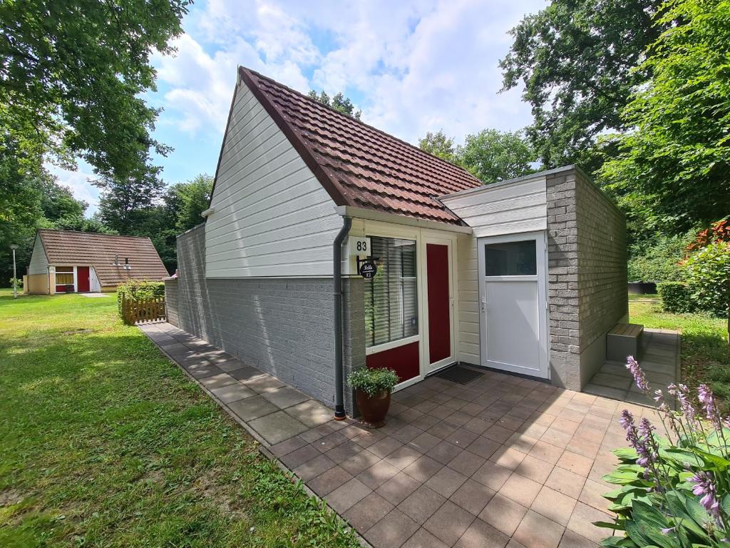 a small shed with a red door in a yard at Belle - Mooi Zuid Limburg in Simpelveld