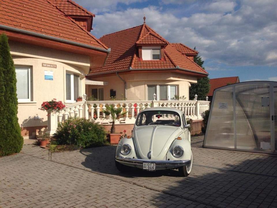 un pequeño coche blanco estacionado frente a una casa en Pihenés Háza-Relax Apartmanhaus, en Gyenesdiás