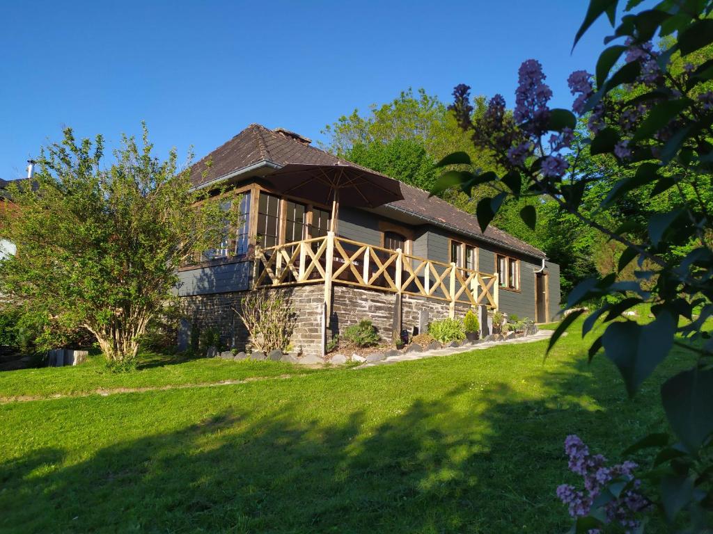 ein großes Haus auf einem grünen Rasen mit Bäumen in der Unterkunft Chalet la Liresse in Rochehaut