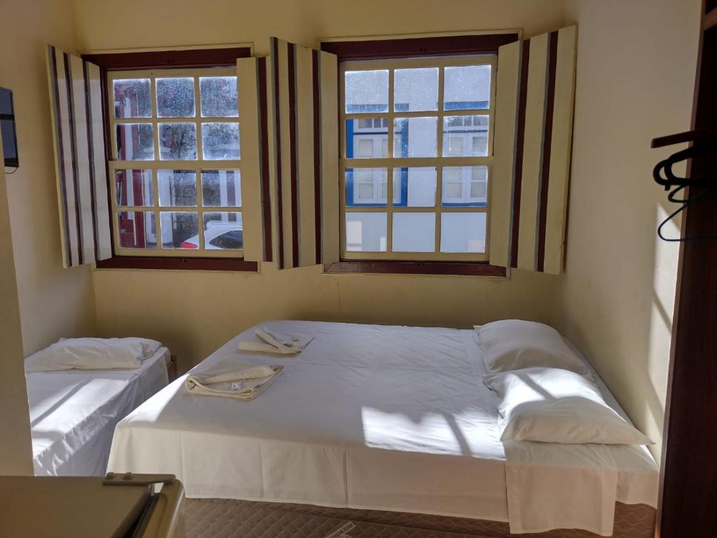 a bedroom with two beds and two windows at Pousada Ouro de Minas in Diamantina