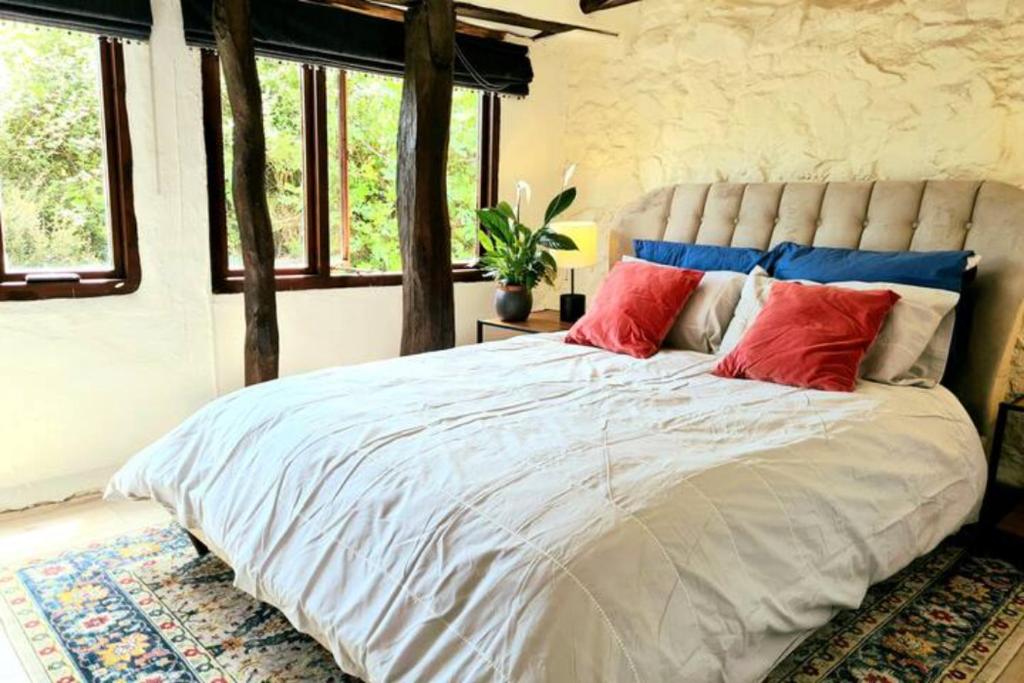 a bedroom with a large bed with red and blue pillows at Historic Property with Stunning Views (Walk to the pub) in Hennock