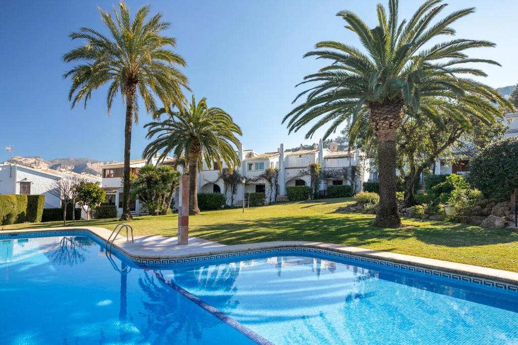 una piscina con palmeras frente a una casa en Bungalow Los Almendros, en Pedreguer