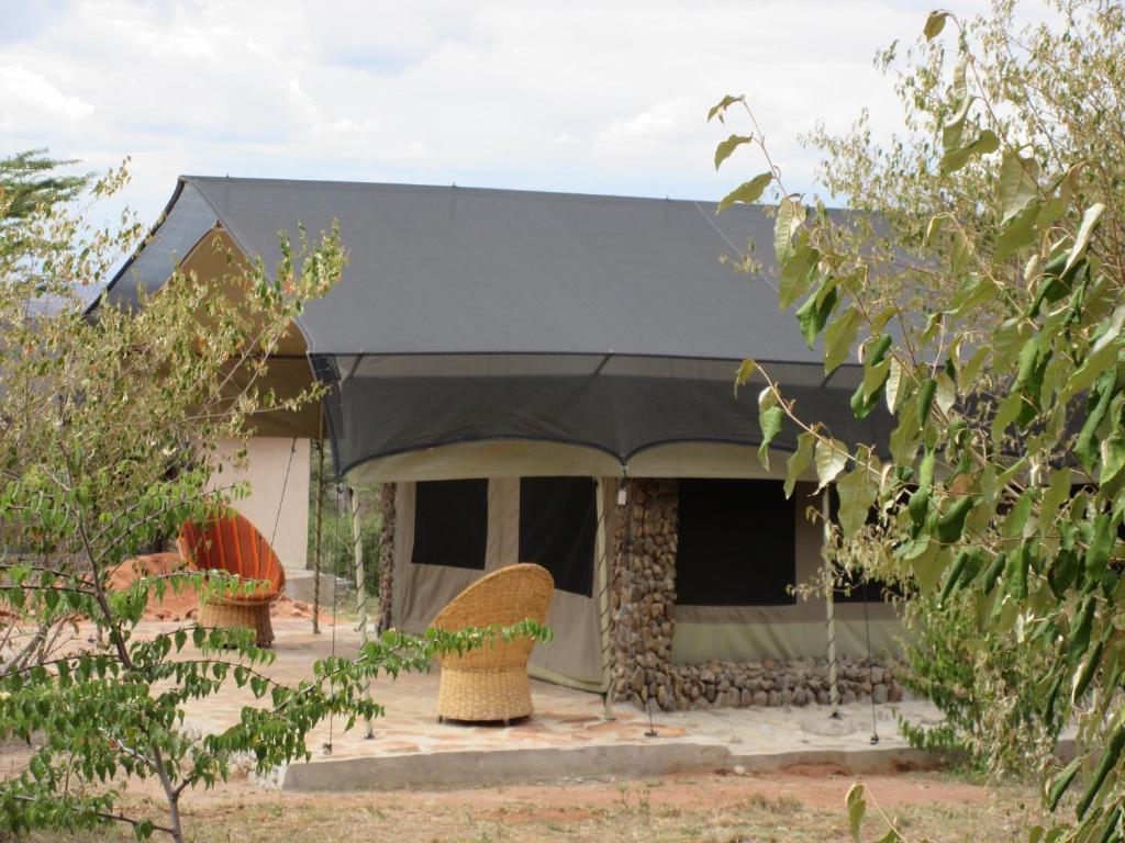 ein Haus mit schwarzem Dach und einigen Pflanzen in der Unterkunft Oseki Maasai Mara Camp in Narok
