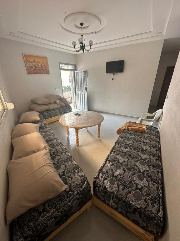 Zimmer mit 3 Betten und einem Tisch in der Unterkunft SAIDIA COSY FLAT in Saidia 