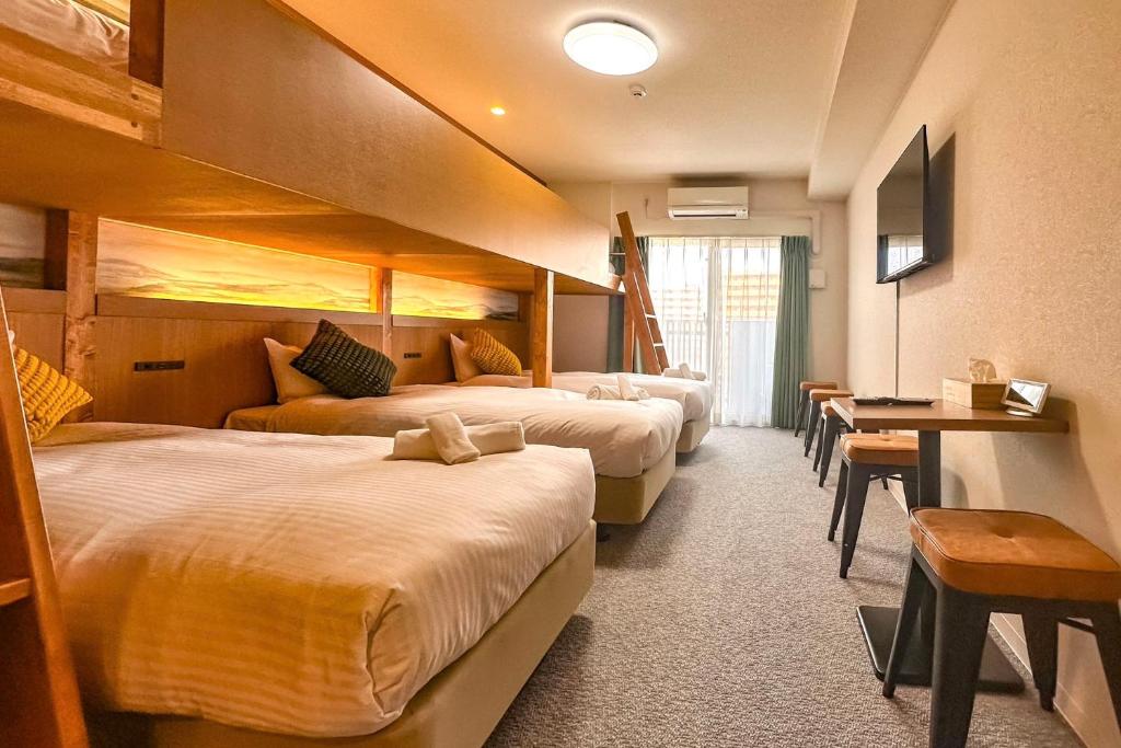 大阪市にあるApartment Hotel 11 Namba Minami Shin-Imamiyaのベッド3台とテーブルが備わるホテルルームです。