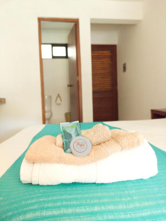 a bed with a towel and a book on it at Casa Yoo Bigu Mazunte in Mazunte