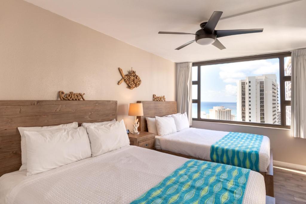 Duas camas num quarto com uma janela grande em Deluxe 32nd Floor Condo - Gorgeous Ocean Views, Free Wifi & Parking! condo em Honolulu