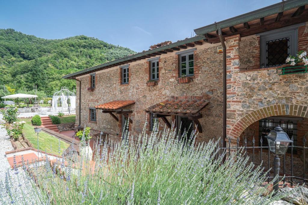 un gran edificio de ladrillo con un jardín delante de él en La Sosta in Toscana en Camaiore