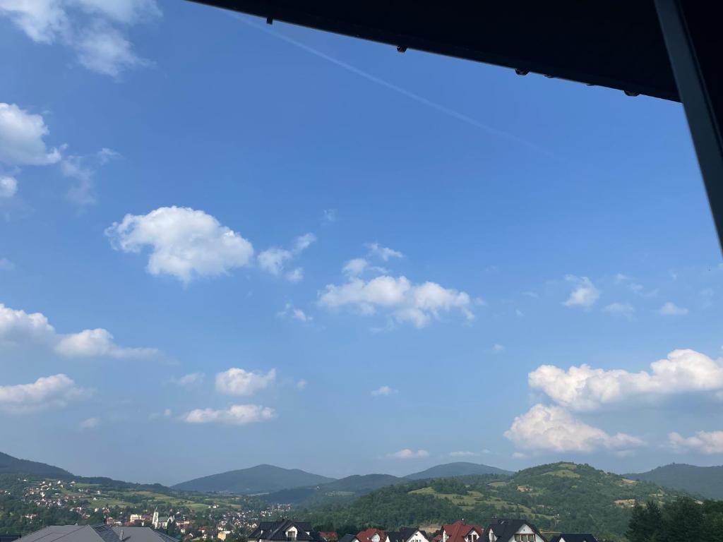 een raam met uitzicht op een blauwe lucht en de bergen bij Lawendowy apartament in Mszana Dolna