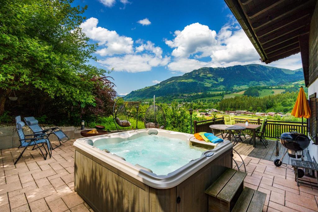 una bañera de hidromasaje en un patio con montañas al fondo en Chalet Mora-lodge by Alpine Host Helpers, en Kitzbühel