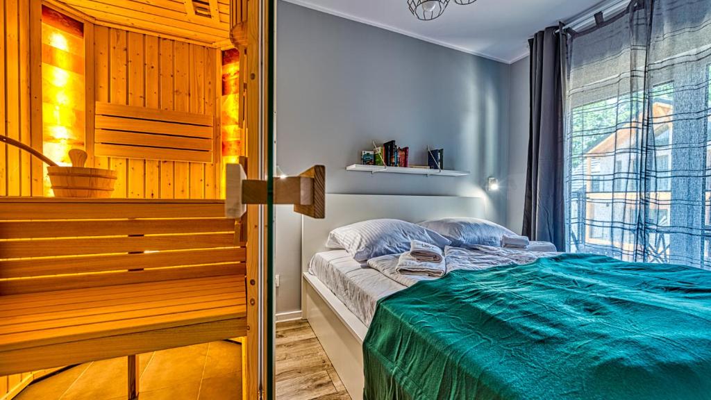 ein Schlafzimmer mit einem Bett mit einer grünen Decke darauf in der Unterkunft Apartament Malachit Osada Górska z prywatną sauną - 5D Apartamenty in Szklarska Poręba
