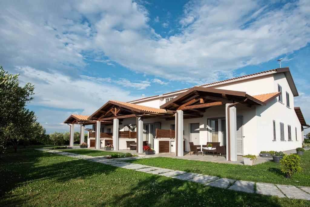 a white house with a wooden roof at Residence Pace & Relax in Marina di Grosseto