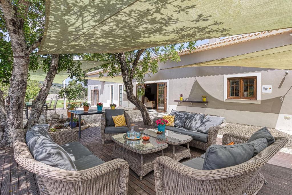 un patio con sillas de mimbre, mesas y árboles en Figs on the Funcho Self Catering - A River side Location, en Pedreiras