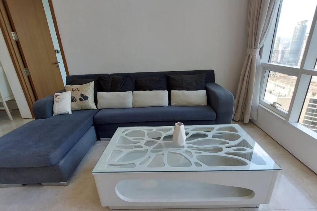 a living room with a blue couch and a table at 5mins to KLCC -Lvl32-2br-FreeParking in Kuala Lumpur