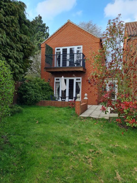 a brick house with a balcony and a yard at Barley View in Aylmerton