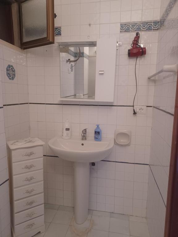 a white bathroom with a sink and a mirror at Casa al centro in Palermo
