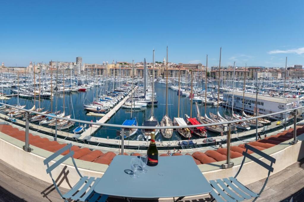 un tavolo con una bottiglia di vino in cima a un porto turistico di Sublime Pépite Vieux Port 2p Vue Imprenable a Marsiglia