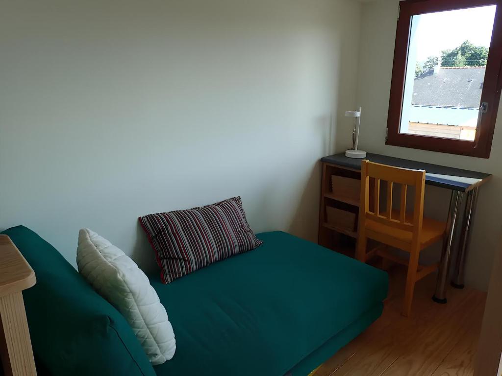 um sofá verde num quarto com uma mesa e uma janela em L'escale Kerhorre em Le Relecq-Kerhuon
