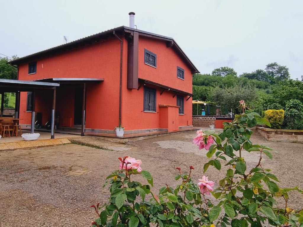 uma casa vermelha com flores cor-de-rosa à frente. em Country house Dolce Nocciola em Vignanello