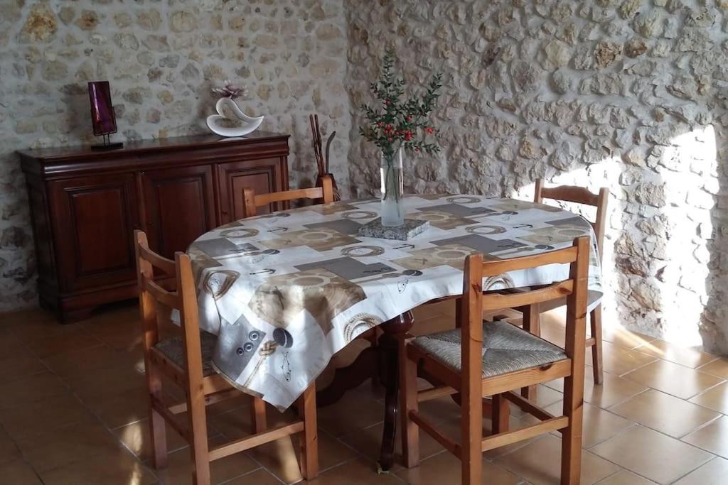 une table de salle à manger avec des chaises et un vase dessus dans l'établissement CHARMANTE MAISON PAISIBLE 6 PERSONNES, à Vendays-Montalivet