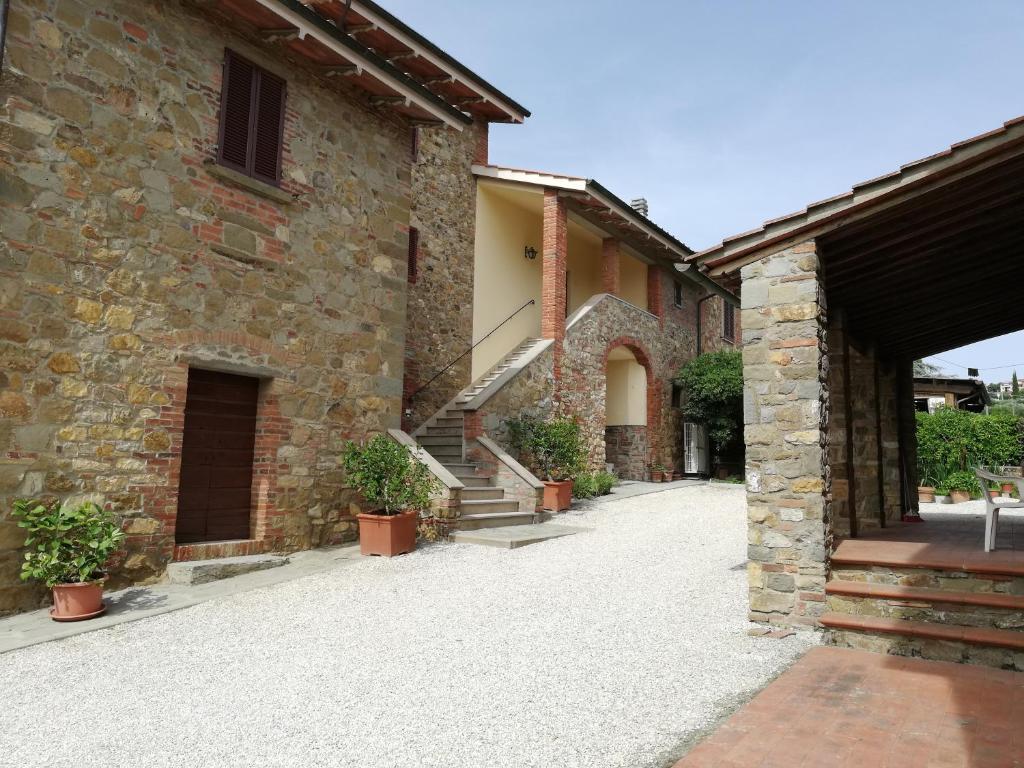 a stone building with a courtyard with potted plants at Il papavero verde in Lucignano