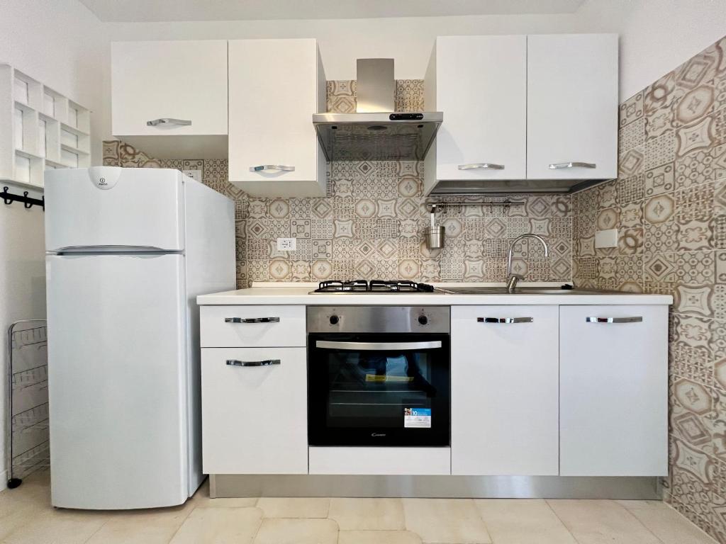 a kitchen with white cabinets and a refrigerator at Mini villino Ladispoli Centro Mare in Ladispoli