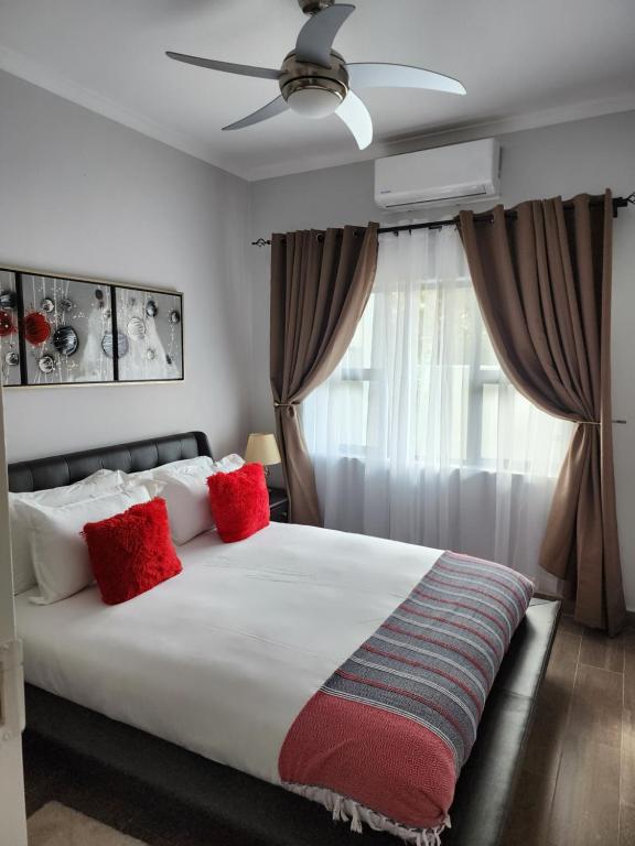 1 dormitorio con 1 cama blanca grande con almohadas rojas en Sarona Studio A103 en Gaborone