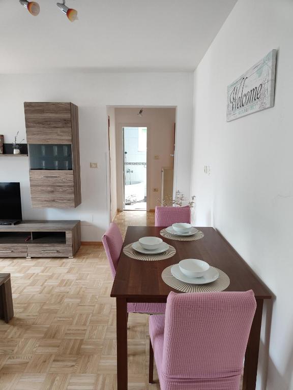 a dining room with a wooden table and pink chairs at Apartma Nena in Bovec