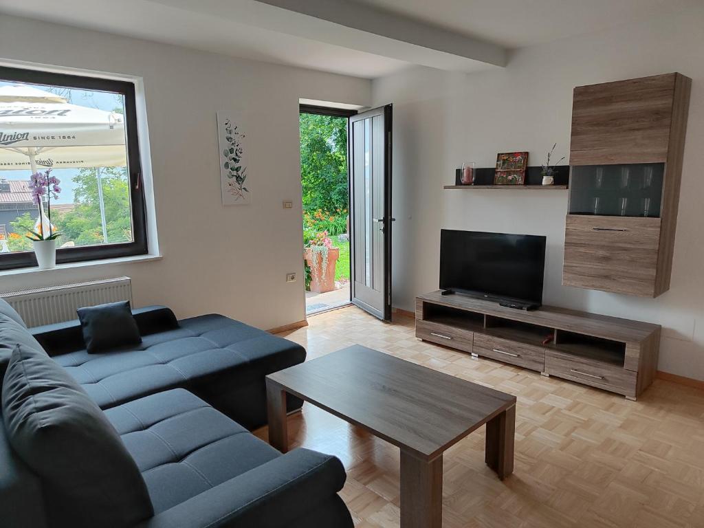 een woonkamer met een bank, een tv en een tafel bij Apartma Nena in Bovec