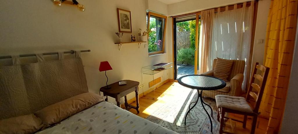 - un salon avec un lit, une table et une fenêtre dans l'établissement Chez Anne, à Rennes