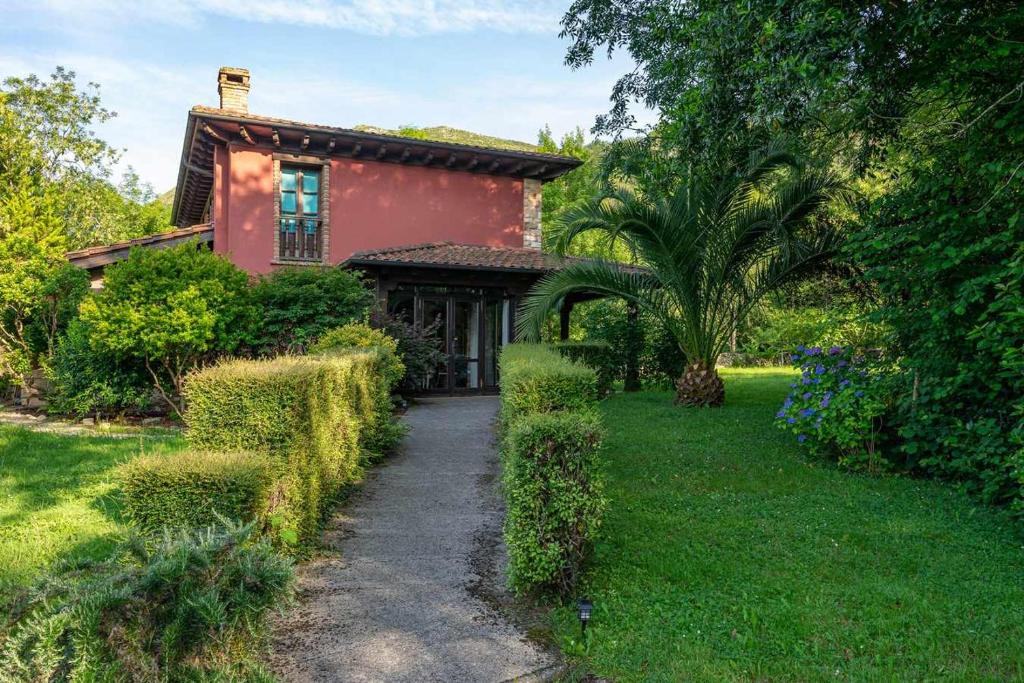 a red house with a pathway leading to a yard at Casa escondida cuencu in Margolles