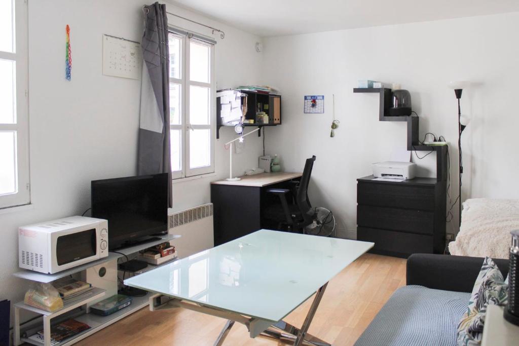 a living room with a glass table and a desk at A cosy little nest in the 5th arrondissement in Paris