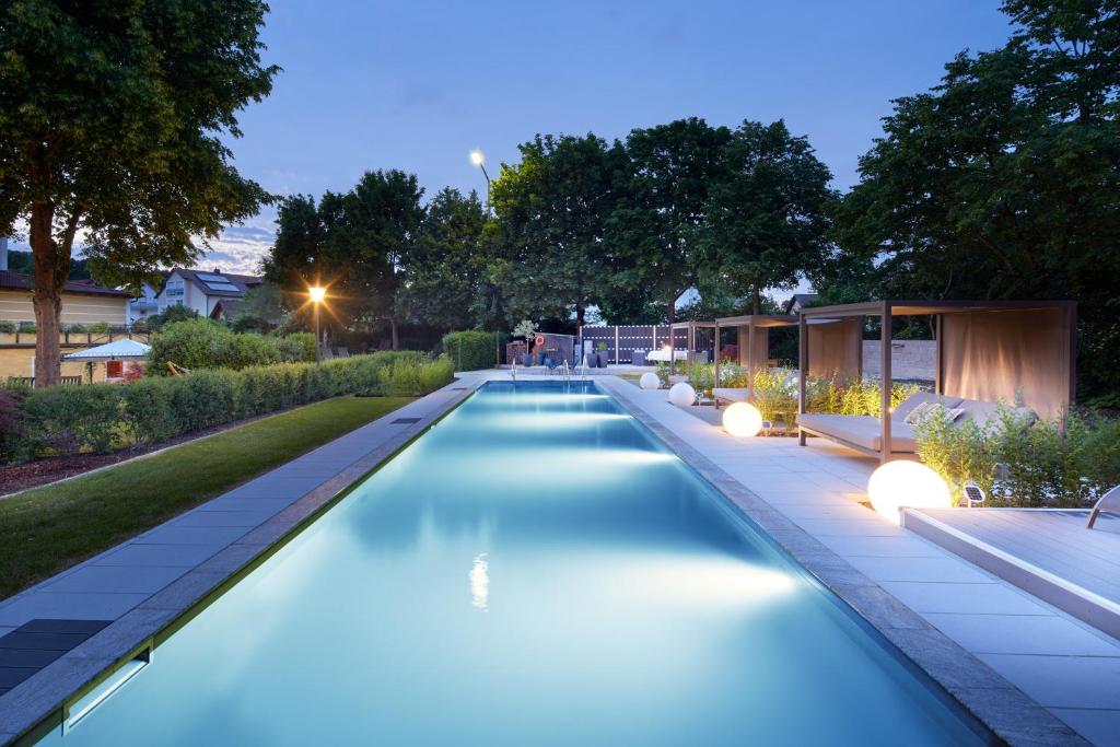 a swimming pool in a garden at night at Garden & SPA Hotel Das Götzfried in Regensburg