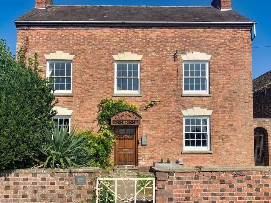 une maison en briques rouges avec une porte brune dans l'établissement Cosy Farm house in Forest of Dean, à Westbury on Severn