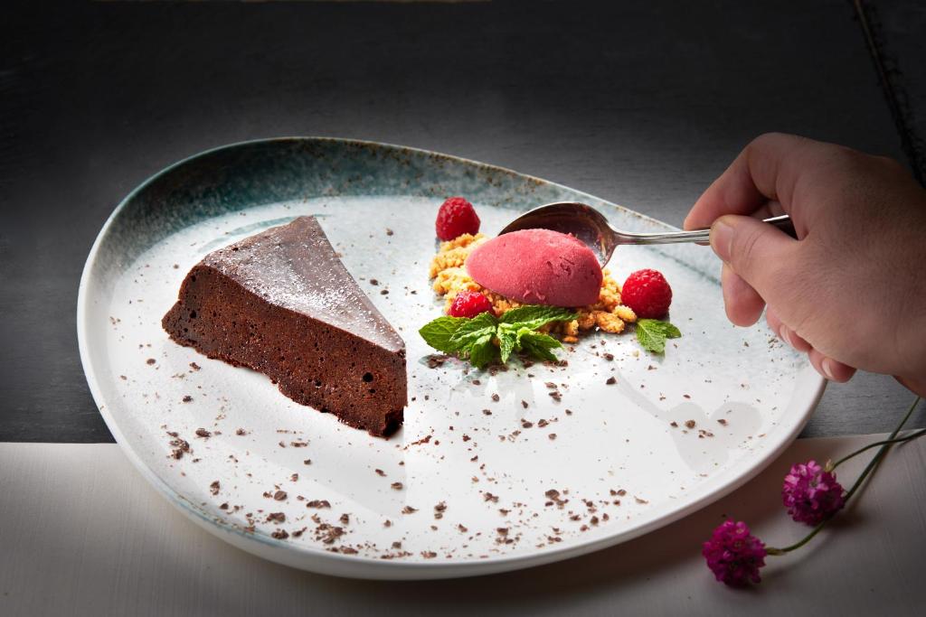 a person eating a piece of chocolate cake on a plate at Garden & SPA Hotel Das Götzfried in Regensburg