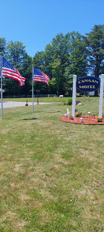 zwei amerikanische Flaggen auf einem Feld neben einem Schild in der Unterkunft Canaan Motel in Canaan