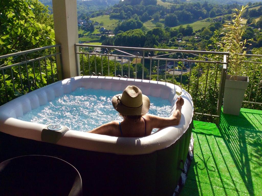 a man in a jacuzzi tub on a balcony at LE PANORAMA et son SPA in Tulle