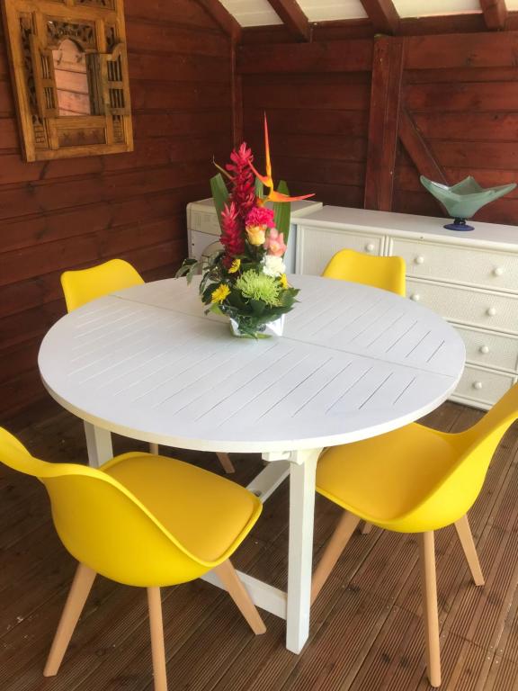 une table blanche avec des chaises jaunes et un vase de fleurs dans l'établissement Tite halte, à Saint-Claude