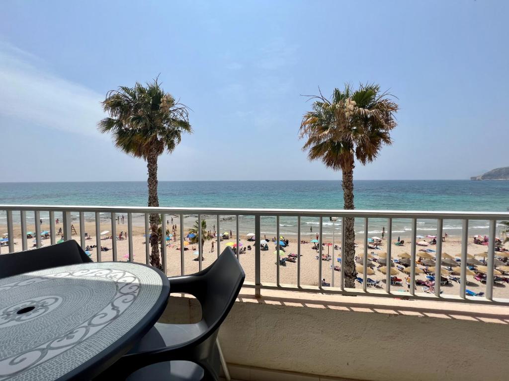 uma vista para uma praia com palmeiras e uma mesa em Apartamento con excelente ubicación y vistas al mar em Calpe