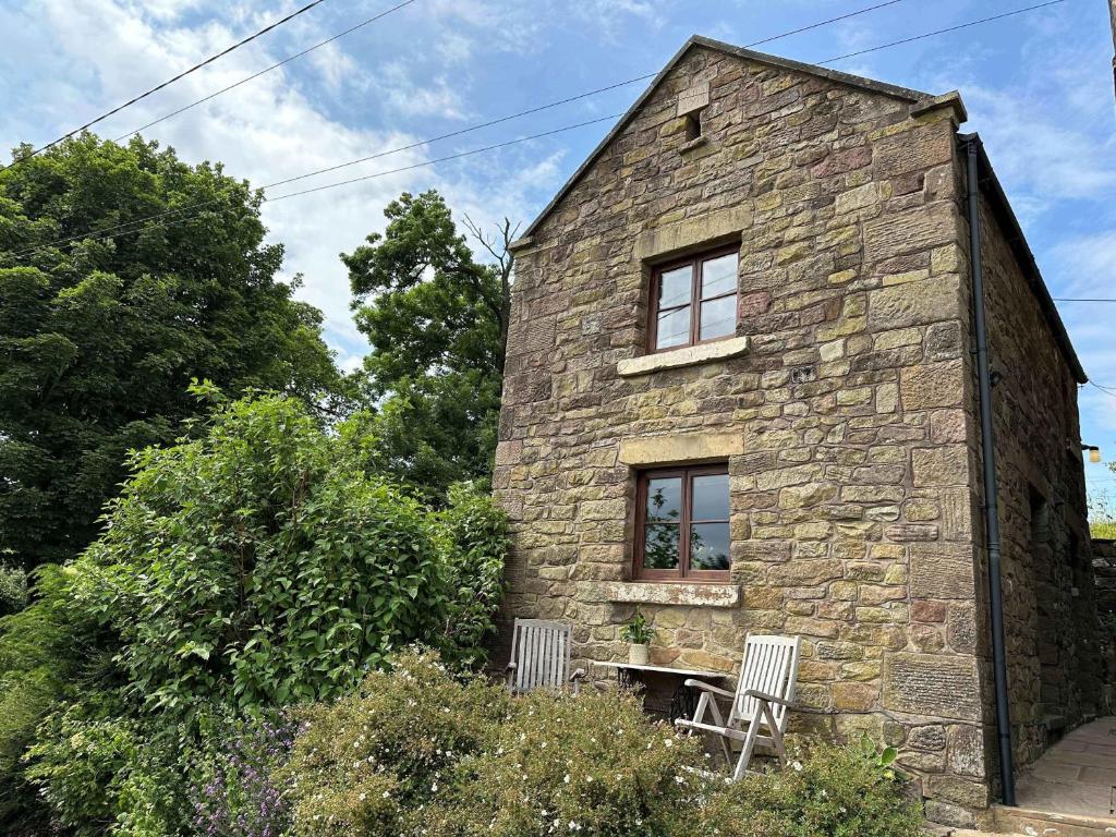 a stone house with two chairs in front of it at Old Post Office Barn in Leek