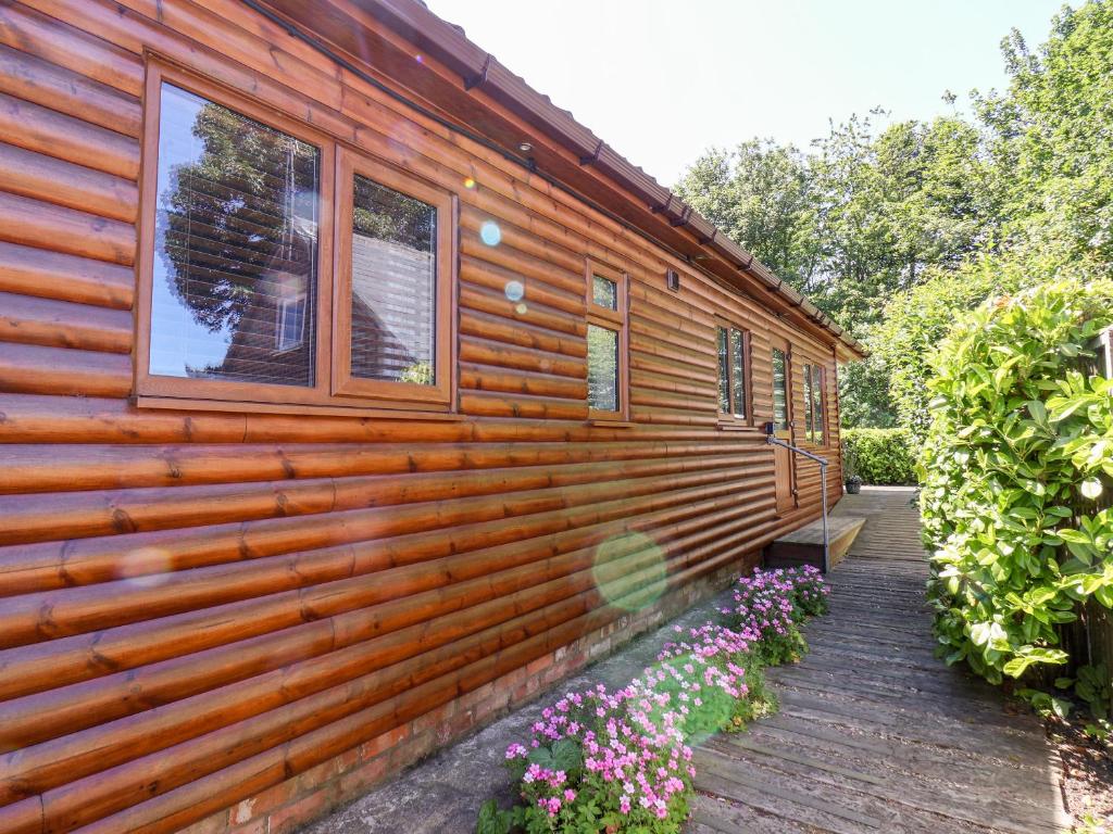 Bempton的住宿－Deer Lodge，木甲板上种有鲜花的小木屋