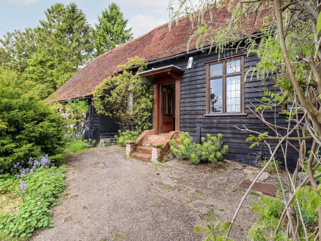 a black cottage with a pathway leading to the front door at Cart Wheel Cottage in Braintree