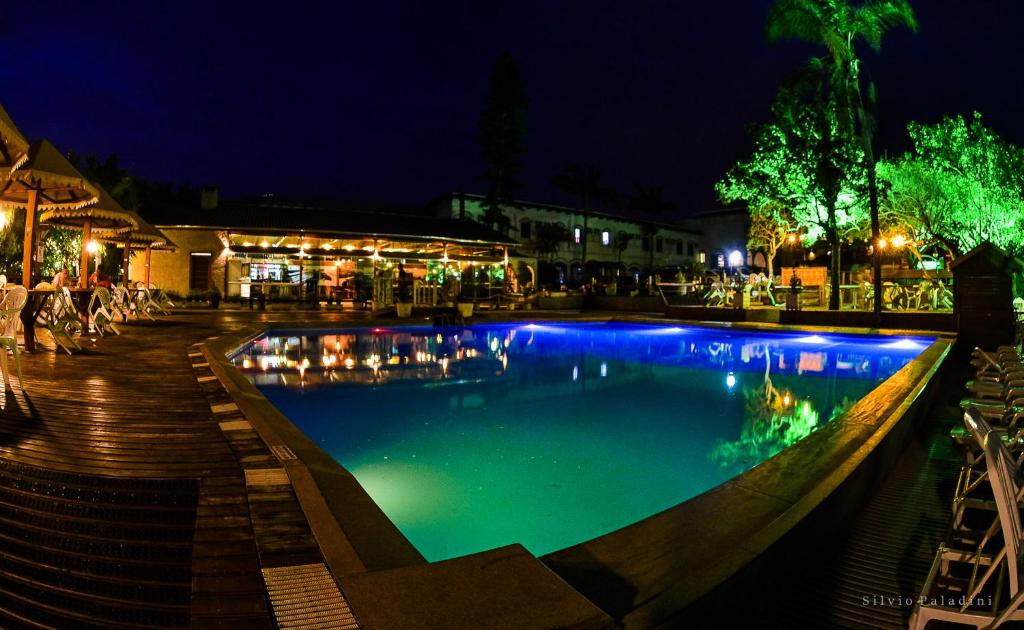 una piscina por la noche con luces en el agua en Hotel Morro dos Conventos, en Araranguá