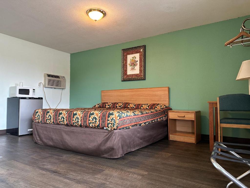 Hillcrist Motel في Aurora: غرفة نوم بسرير في غرفة بجدران خضراء