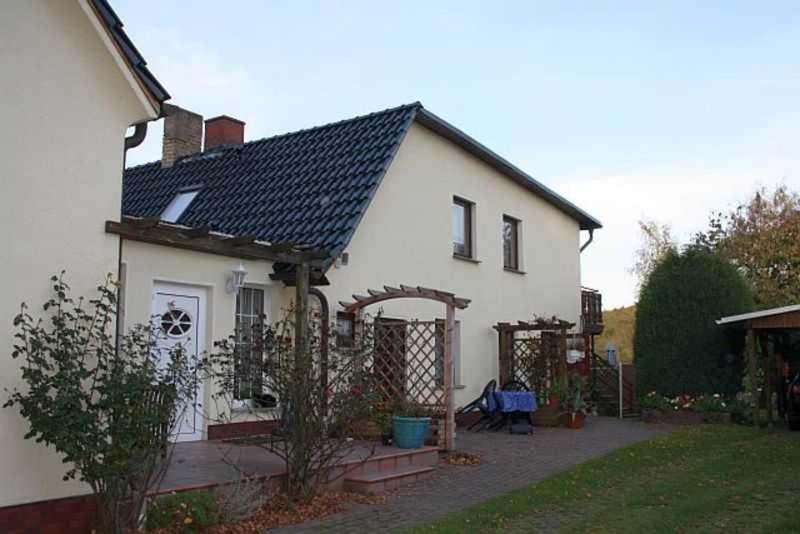 una casa blanca con un arco y un patio en 2 Ferienwohnungen am Bodden (Nr.86), en Ralswiek