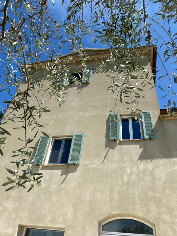 a building with blue shuttered windows and a tree at L'Antica Colombaia; Apartment with private entrance in Ostra