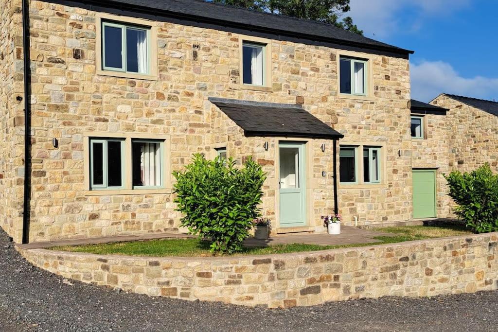 a stone house with green doors and windows at Coolams in Ingleton