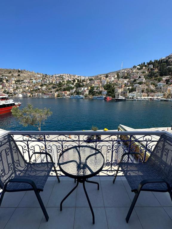 einen Tisch und Stühle auf einem Balkon mit Blick auf einen Wasserkörper in der Unterkunft Cavo apartment in Symi